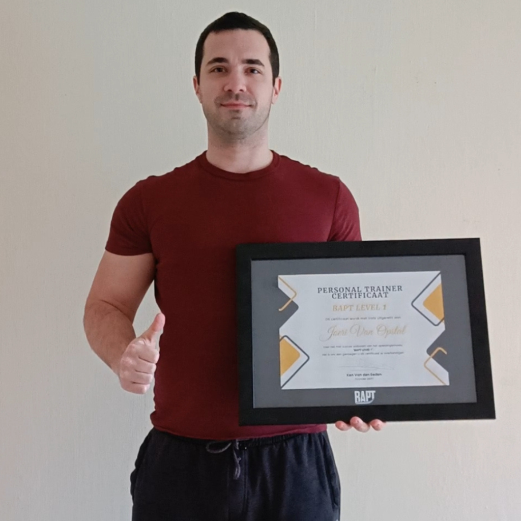Man houdt een ingelijst personal trainer-certificaat vast en steekt zijn duim op