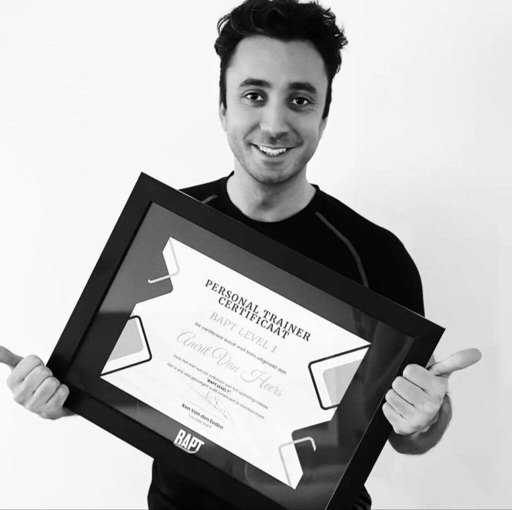 Glimlachende man houdt een ingelijst personal trainer-certificaat vast en steekt duimen op