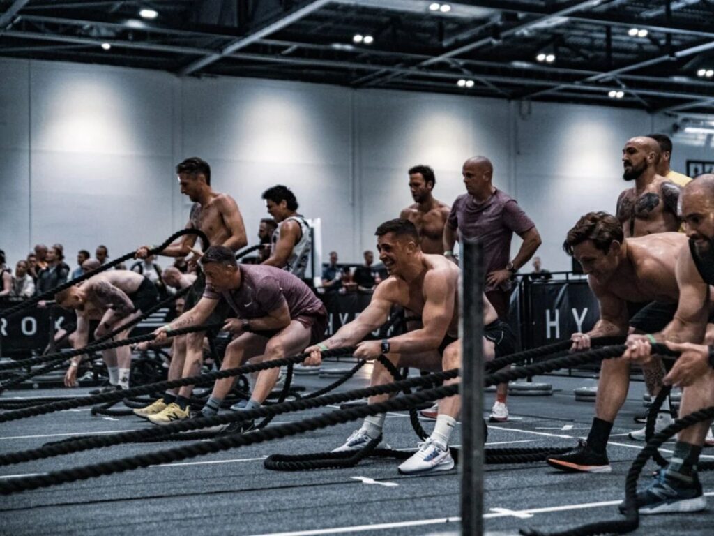 Sporters doen battle ropes tijdens een intensieve groepswork-out.