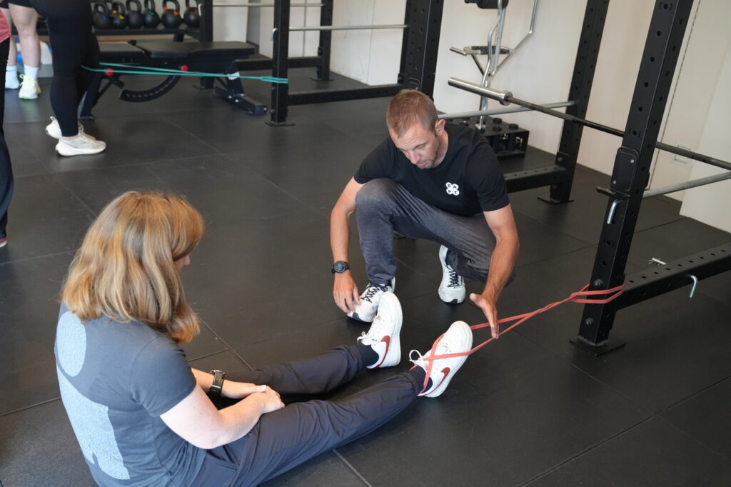 BAPT master trainer helpt cursist met bandoefening op de grond