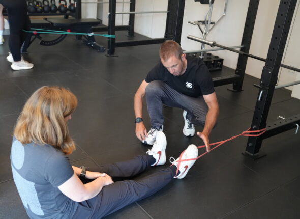 BAPT master trainer helpt cursist met bandoefening op de grond